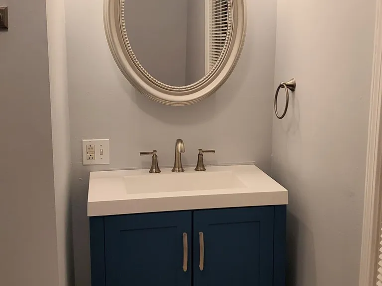 Brand new blue vanity and gray laminate flooring in full bath.