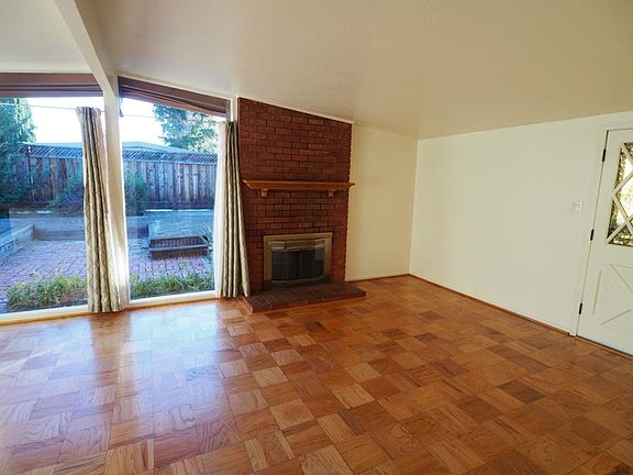 Wood burning fireplace in living room. Parquet hardwood floor throughout house.
