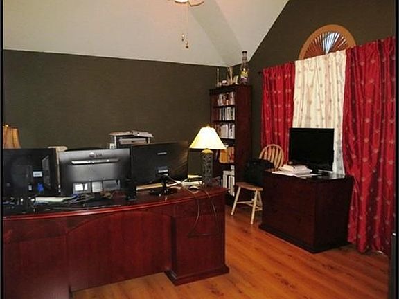 Study has laminate wood floors, high ceilings and ceiling fan.