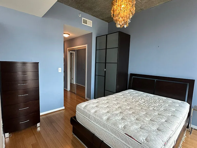 Bedroom and closet with sliding mirrored doors in the hallway. Washer/dryer next to closet.
