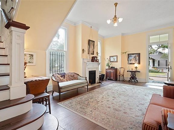 Living room featuring an inviting chandelier, ornamental molding, decorative columns, and dark hardwood / wood-style flooring