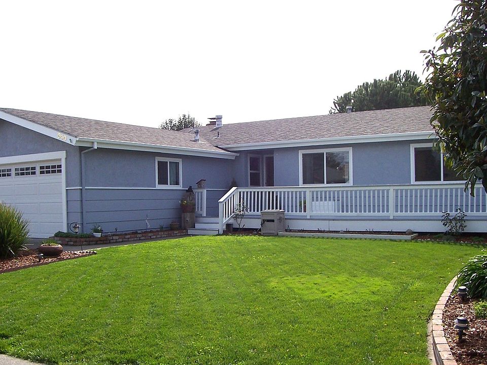 Nicely landscaped front yard with newer front deck and a large grassy area.