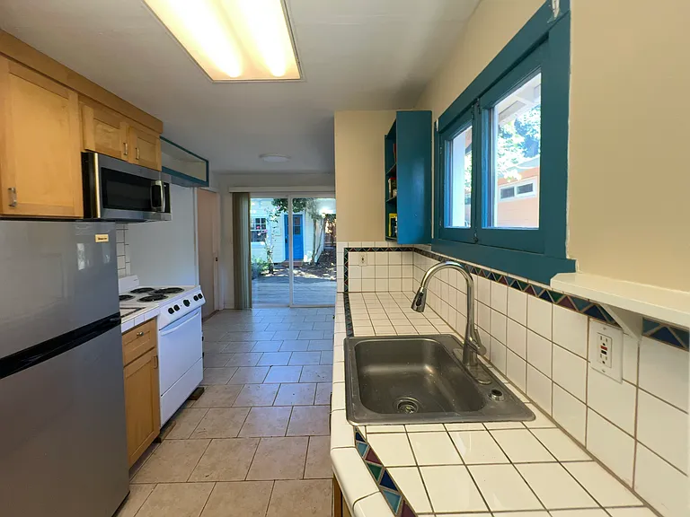 Kitchen has up-to-date appliances: refrigerator, microwave, range, and stainless steel sink. The washer & dryer are in the basement.