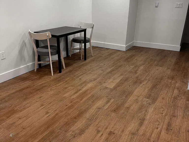 Open common area with durable wood-style flooring and recessed lighting, plus a compact table for dining or work.