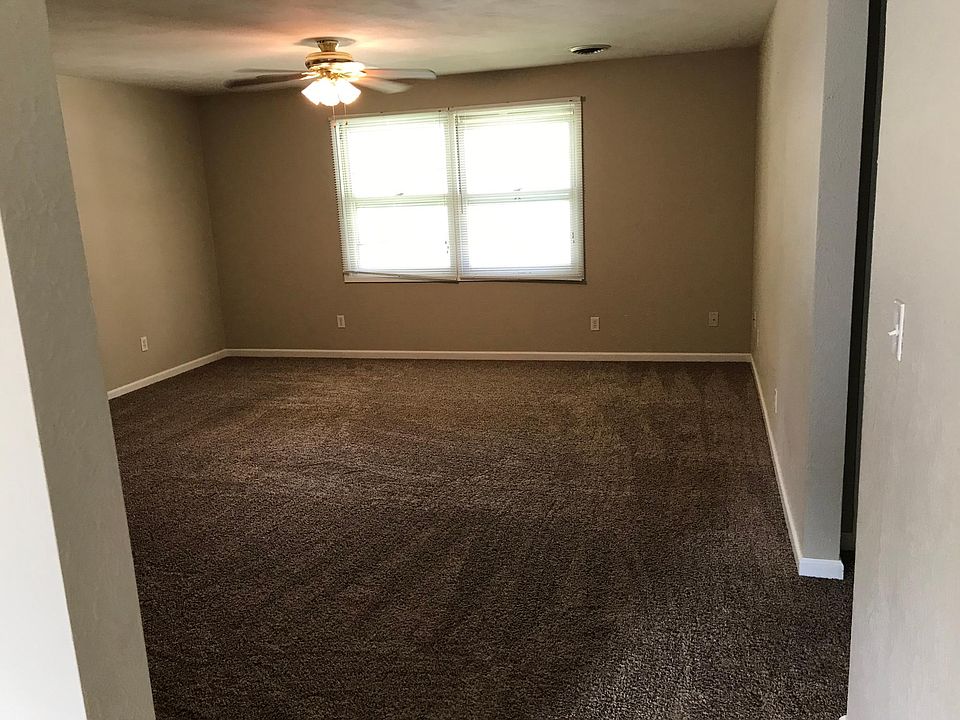 View of spacious Living room, taken from adjoining Kitchen, showing double front windows and ceiling fan.