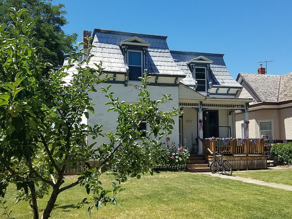 french colonial style with front porch swing and fruit trees