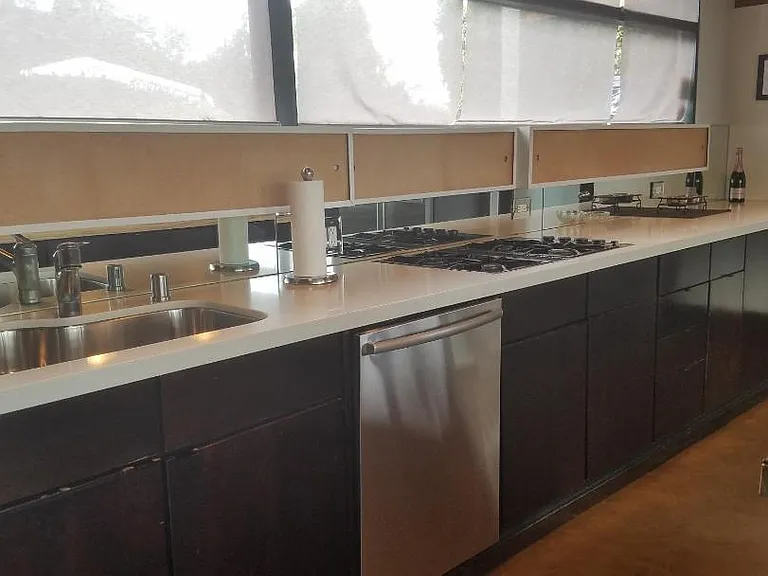 Mid-century style custom kitchen featuring original upper storage cabinets, mirrored backsplash, Bosch dishwasher, and JennAir gas cooktop.