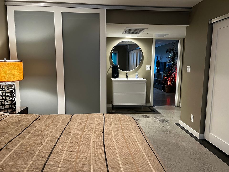 Modern frosted glass barn door in open position with floating vanity and living area beyond.