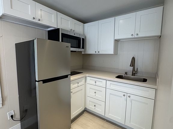 Kitchen features fridge/freezer, microwave, and two burner cooktop with ample cabinet space.