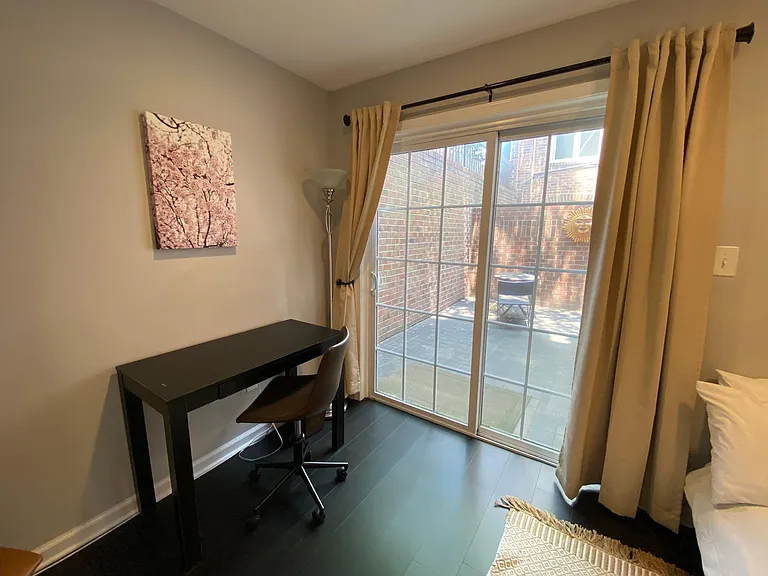 Bedroom #2 with a double sleigh bed, desk, lounge chair and sliding door to patio.