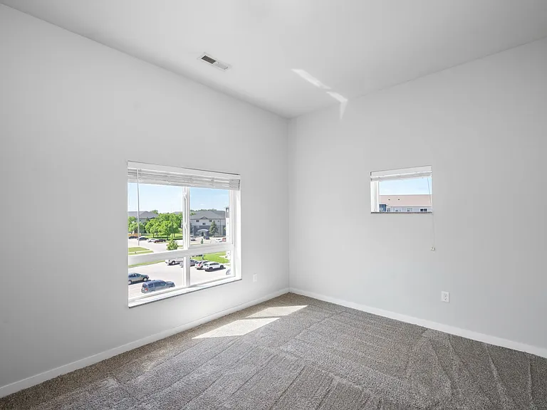 Bright and airy bedroom with large windows offering panoramic views, featuring fresh carpeting and neutral walls for a modern look. Bright and airy bedroom with large windows offering panoramic views, featuring fresh carpeting and neutral walls for a mode