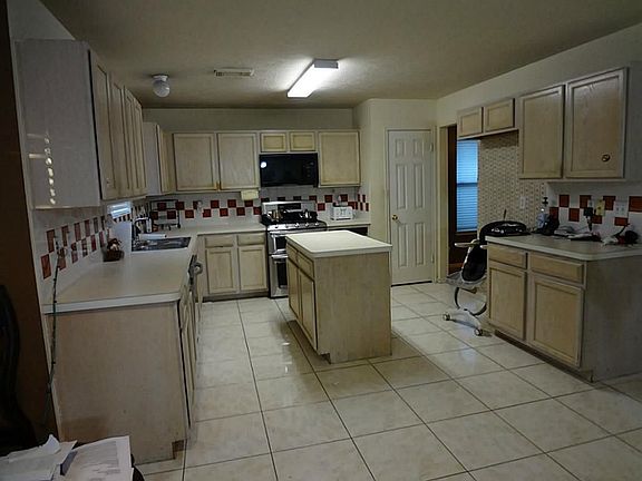 Huge island kitchen w/ newer stainless appliances. Fridge to remain with home also.