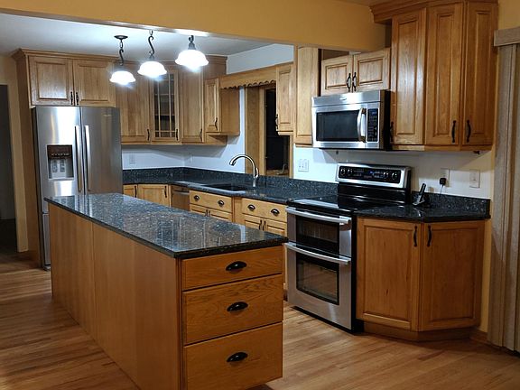 Kitchen with granite countertops, double oven, stainless appliances, refrigerator with icemaker, island