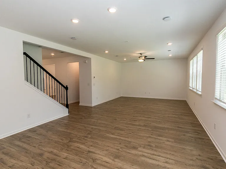 Bright living room featuring wood floors and large windows, perfect for gathering and entertaining.