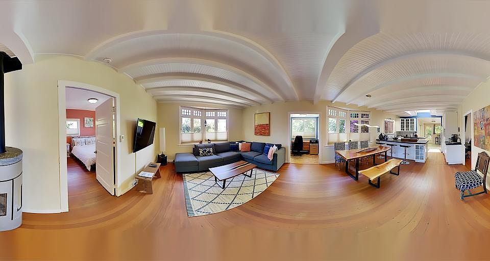 Open layout kitchen dining and living room with the original 100-year-old wood floor, beamed ceiling, bay windows and modern glass fireplace/furnace