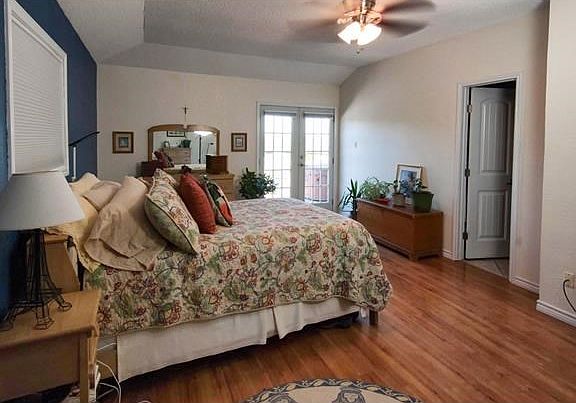 The master bedroom, shown here, includes French door access to the deck and pool. With space for a seating area, a crisp white and blue color scheme and views of the Texas Hill Country this master bedroom can become a retreat spot at the end of your day.