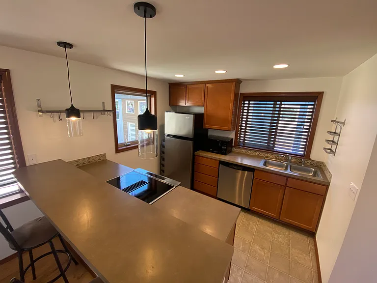 2nd Floor _ Open-concept living area featuring sleek hardwood flooring, a cozy tiled fireplace, a kitchen with stainless steel appliances and a premium slide-in electric range, plus a convenient half bathroom.