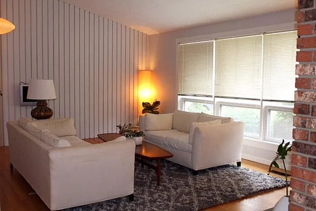 sunny living room faces front of house, vaulted ceiling, vertical panel feature wall, gets afternoon sun. working fireplace.