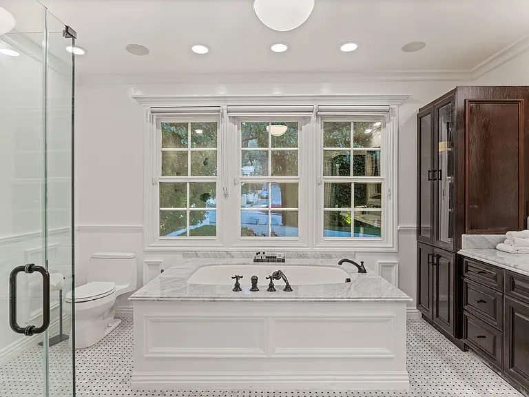 Treat yourself to a bathing extravaganza in this luxurious bathroom, boasting a deep soaking tub and captivating marble details.