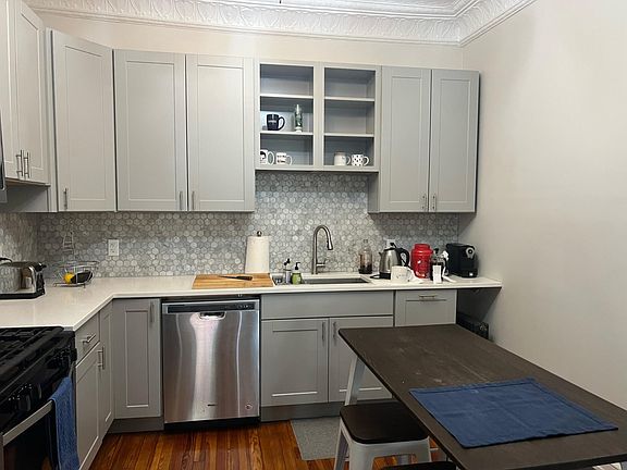 Modern kitchen. Grey shaker style cabinets, marble tile backsplash, stone counters, and updated stainless steel appliances