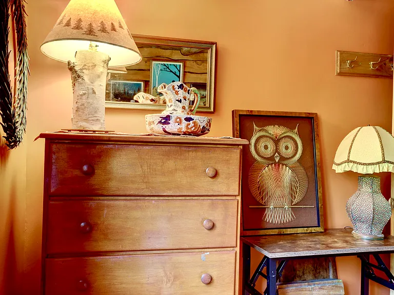 Guest bedroom with tall pine bureau with Birch log lamp, mirror, vintage table lamps and 1970s string painting of an owl.