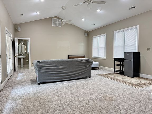 Spacious 600 sq ft bedroom with vaulted ceilings, plenty of natural light from 5+ windows, and bright overhead lighting.