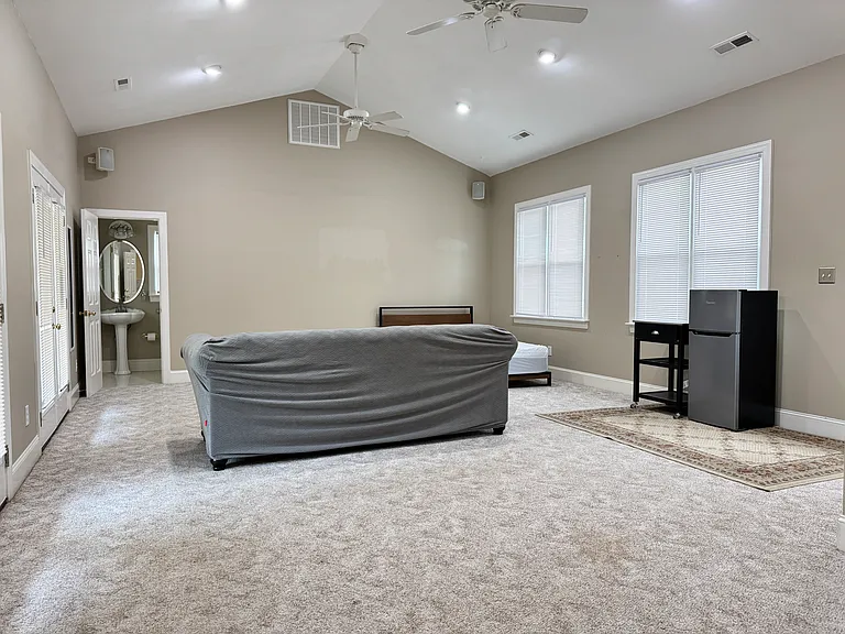 Spacious 600 sq ft bedroom with vaulted ceilings, plenty of natural light from 5+ windows, and bright overhead lighting.
