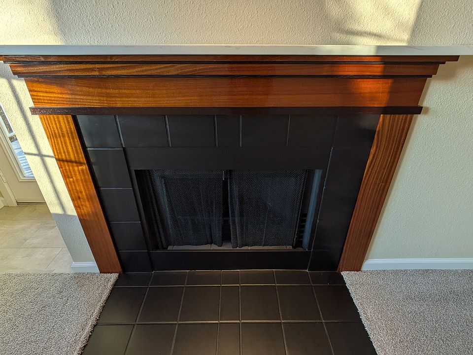 Wood burning fireplace with surround constructed of African hardwoods (sapele and wenge), and quartz mantle