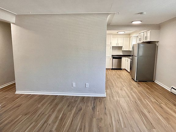 Modern open-plan kitchen area with sleek stainless steel appliances and warm wood flooring, perfect for contemporary living.