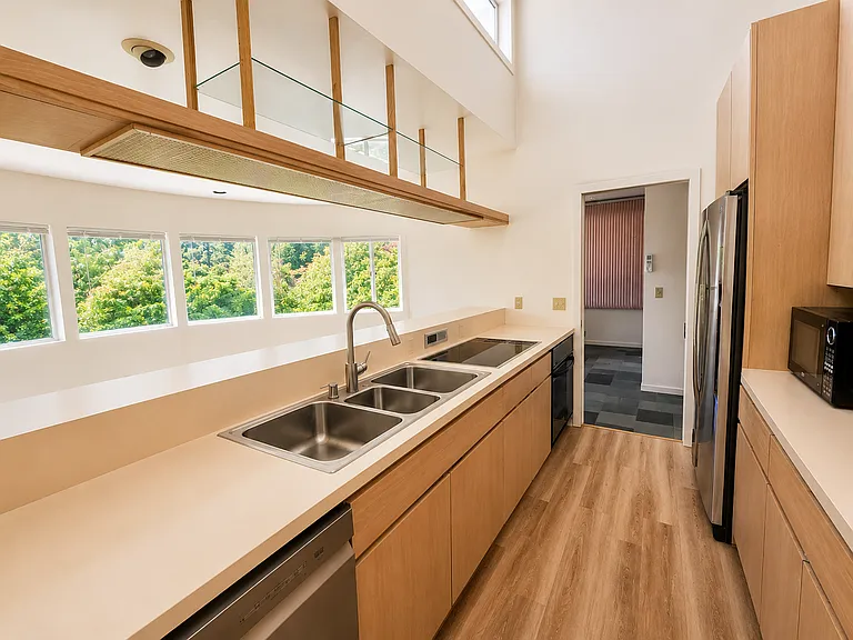 View of the kitchen from the dining room, with the living room to the left and the entry at the other end.