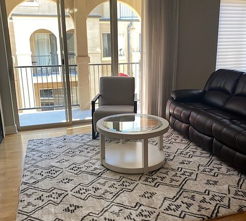 Living room is furnished and offers cozy sitting room with double doors opening to the balcony. The balcony overlooks the courtyard and offers a mountain view.