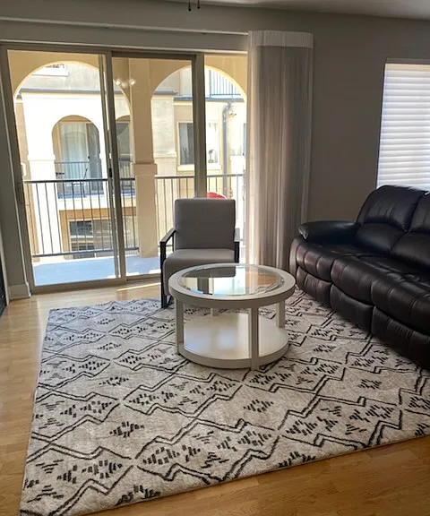 Living room is furnished and offers cozy sitting room with double doors opening to the balcony. The balcony overlooks the courtyard and offers a mountain view.