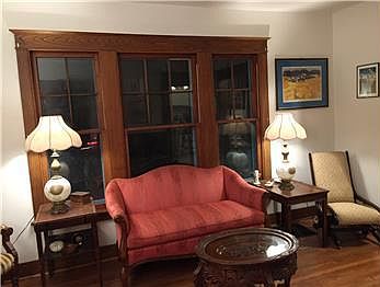 Spacious living room with original wood paneled windindows