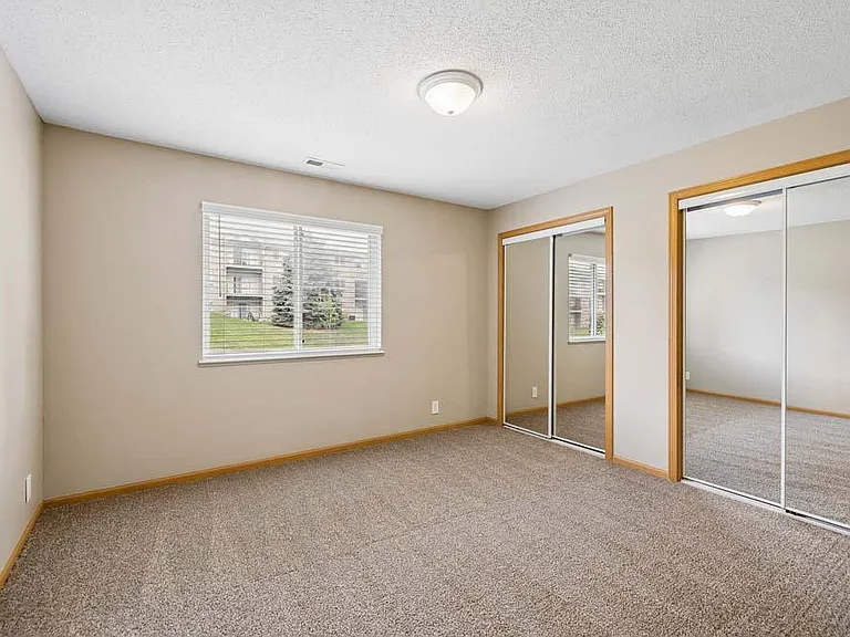 Mirrored closet doors, soft natural light, and a spacious layout come together to create a bedroom that feels bright, open, and effortlessly comfortable.