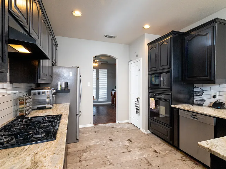 Bright kitchen with black cabinets, stainless appliances, and a curved breakfast bar with seating. Perfect for cooking, gathering, and enjoying meals together.