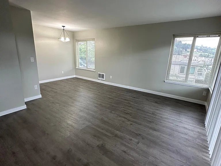 Large living room with balcony and dining room area. West facing balcony and windows and south facing windows in the living and dining area.