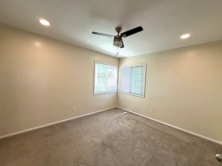 Bedroom with corner windows and ceiling fan for great natural light and breezes. New recessed lighting.