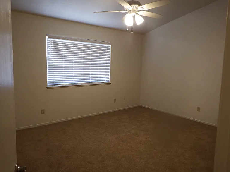 Master bedroom with large window and ceiling fan/light.