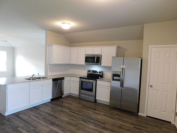 Beautiful kitchen features white shaker cabinets, granite countertop, stainless appliances including a side-by-side refrigerator with ice/water in the door. The door to the right in picture is the pantry. Flooring throughout is wood-look luxury vinyl pl