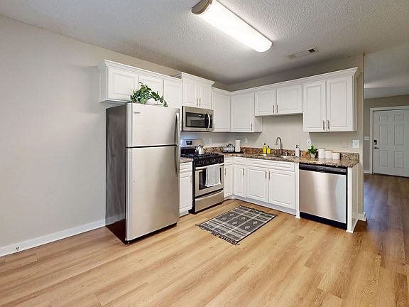Experience the charm of a huge kitchen and dining area adorned with abundant white cabinetry and granite-inspired countertops for a delightful cooking and dining journey.
