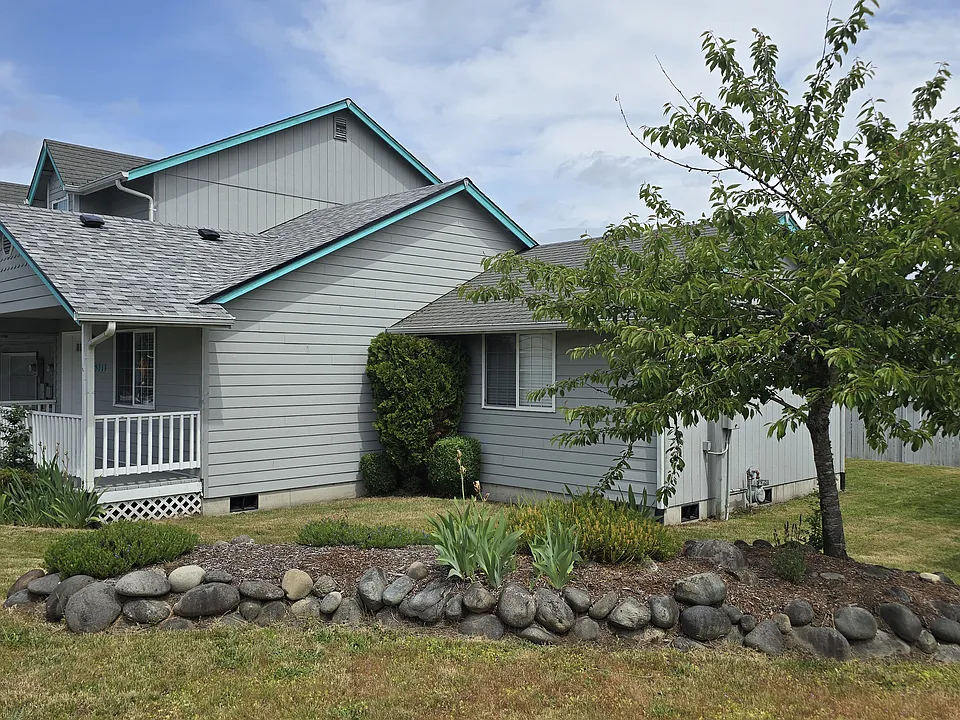 Side view. Front, side, back lawn. Flower bed and tree