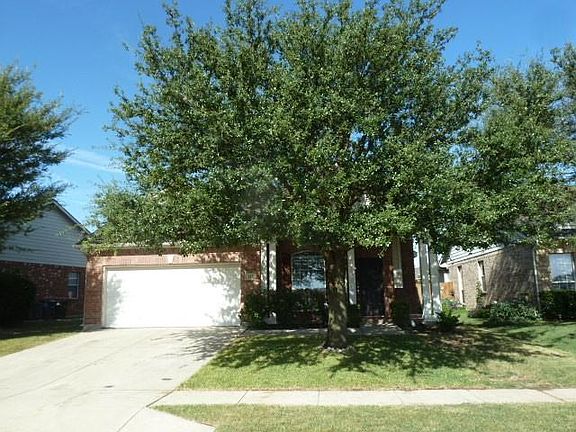 View of property hidden behind natural elements featuring a front yard and a garage