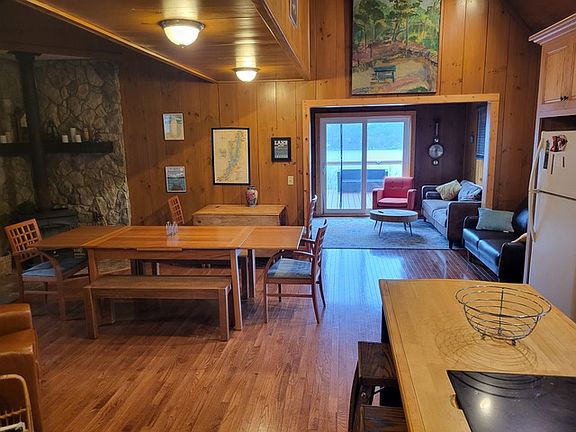 Dining area with hardwood / wood-style flooring, a wood stove, and wooden walls