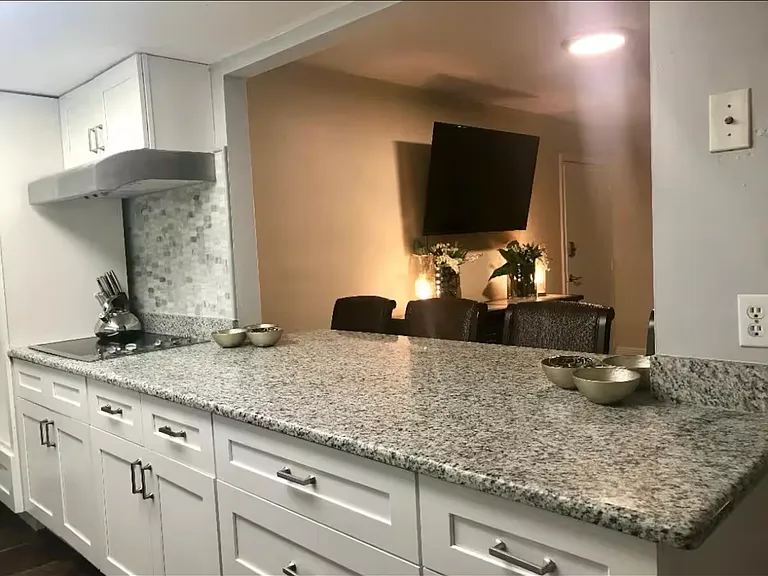 The large galley style kitchen has New, wood, white shaker style cabinets. It boasts granite countertops as well as a wall oven.