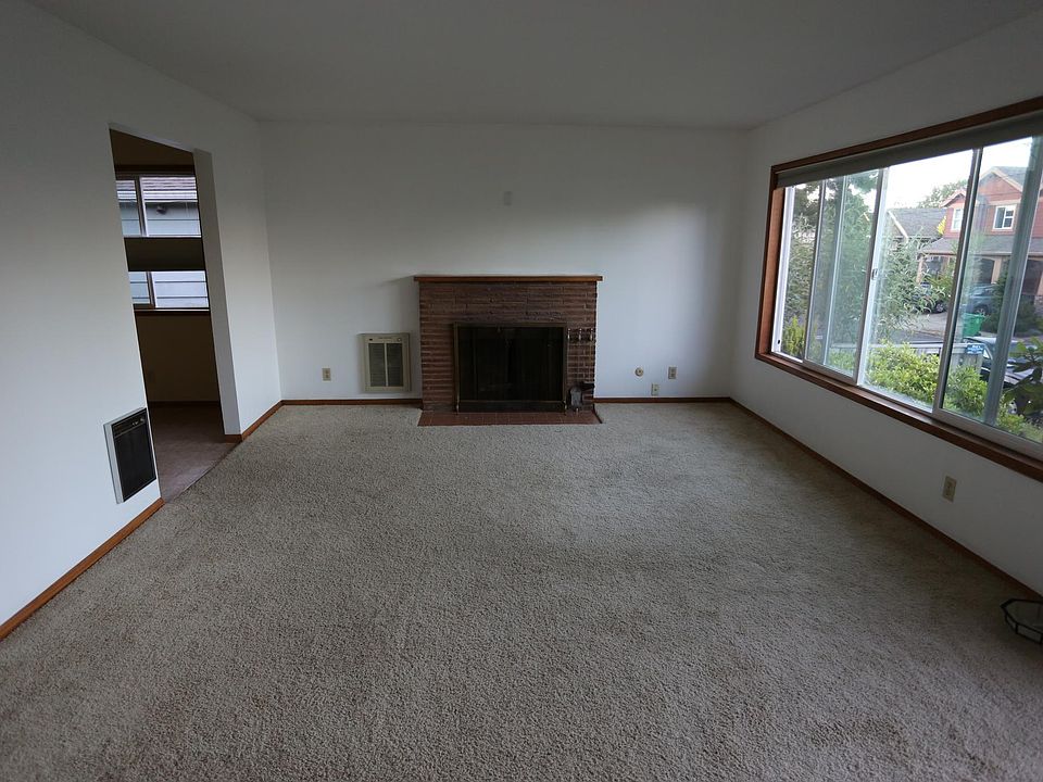 Living room with fireplace, windows facing east, dining area in room to left.