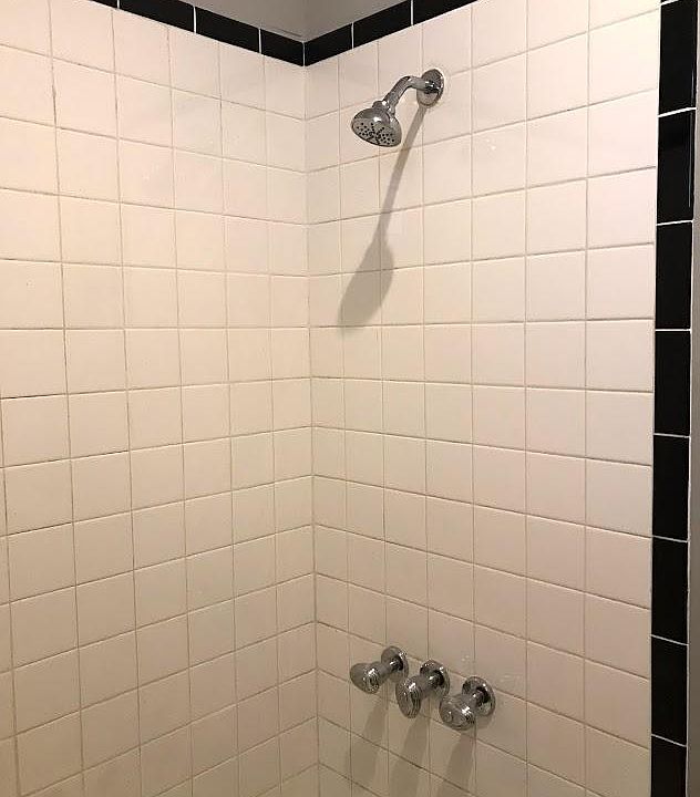 New shower head and faucet, tiled walls.