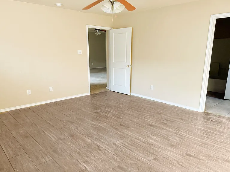 Master bedroom brand new ceramic wood tile flooring, fan/light and door toward the living area.