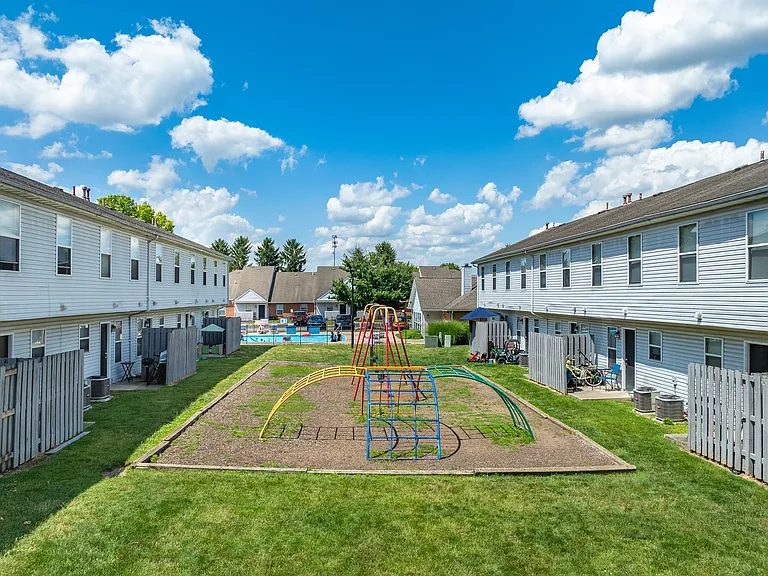 A playground with a swing set in the middle of a grassy area at River Valley Apartments in Lancaster, OH.
