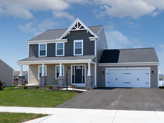 Front view of a two-story home with a gray and tan exterior, stone-accented porch columns, white tri