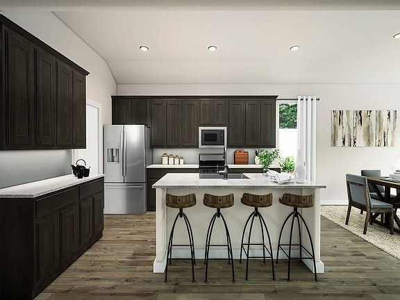 A modern and sleek kitchen with dark wood cabinets, a white island with bar stools, and a dining are